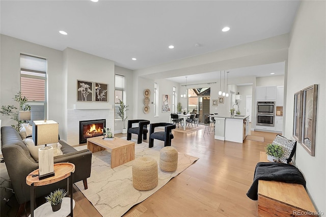 living area with light wood-style floors, recessed lighting, and a glass covered fireplace