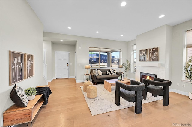 living area featuring recessed lighting, a brick fireplace, baseboards, and light wood finished floors