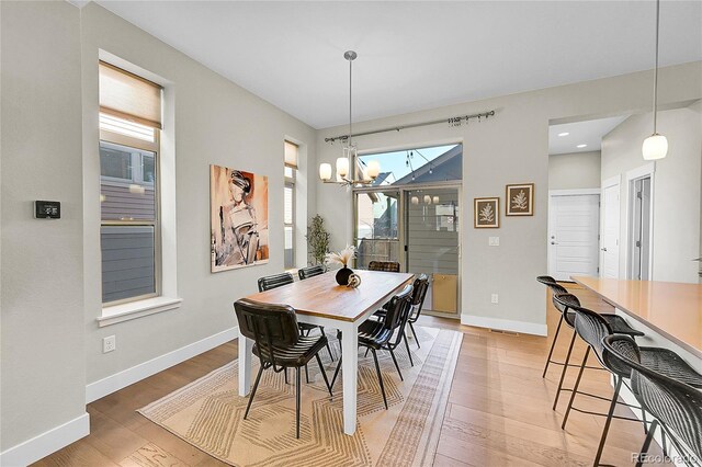 dining room featuring an inviting chandelier, light wood-style flooring, and baseboards