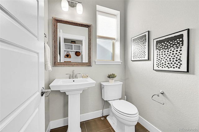 bathroom featuring tile patterned flooring, baseboards, a sink, and toilet