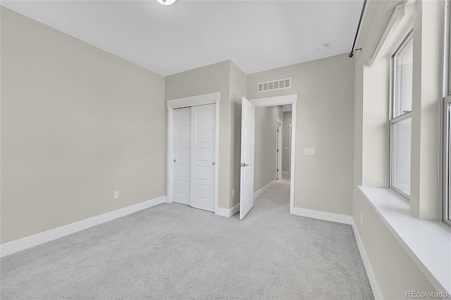 unfurnished bedroom with a closet, carpet flooring, visible vents, and baseboards