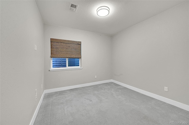 carpeted empty room with visible vents, a textured ceiling, and baseboards