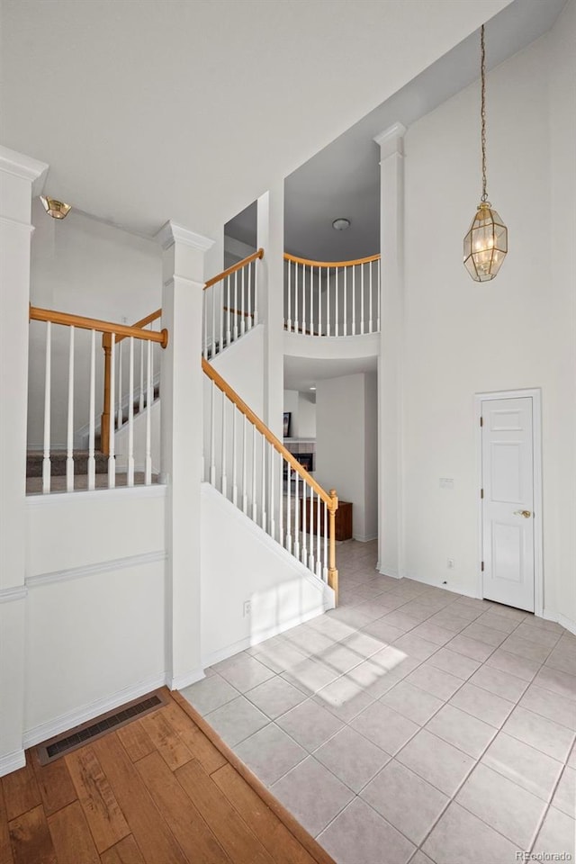 foyer featuring light tile patterned floors, a towering ceiling, and decorative columns