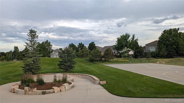 view of home's community with basketball hoop and a yard