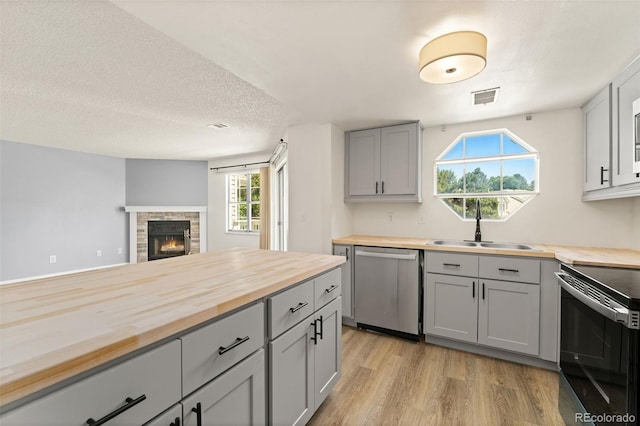 12573 E Pacific Cir Unit C, Aurora, CO 80014 - kitchen featuring butcher block counters, appliances with stainless steel finishes, gray cabinetry, light wood-style flooring, and a textured ceiling