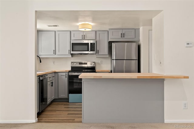 12573 E Pacific Cir Unit C, Aurora, CO 80014 - kitchen with appliances with stainless steel finishes, gray cabinets, wooden counters, and a peninsula