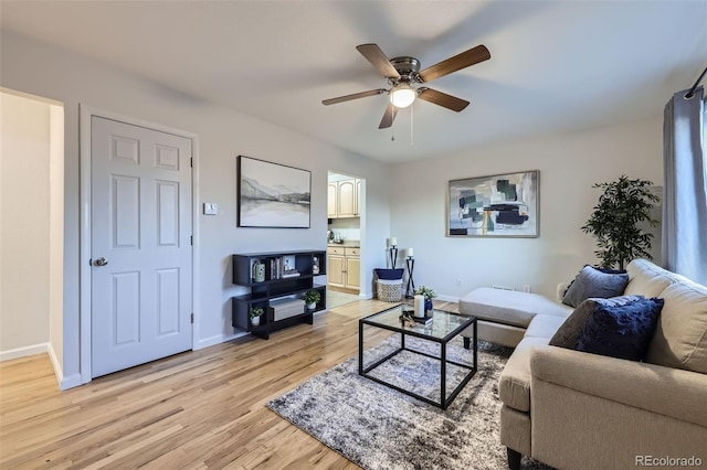 living room featuring light wood-style floors, baseboards, and ceiling fan