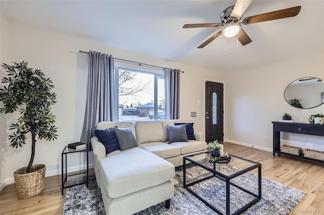 living area with ceiling fan, baseboards, and light wood-style floors