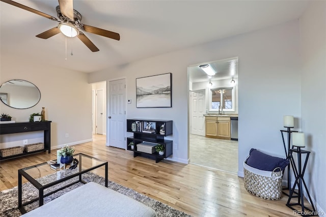 living area featuring baseboards, light wood-style floors, and ceiling fan