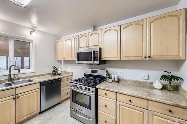 kitchen featuring a sink, light countertops, stainless steel appliances, and light brown cabinetry