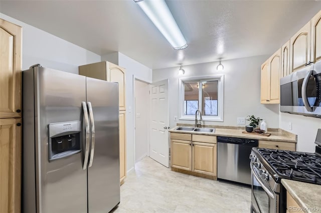 kitchen with light countertops, light brown cabinets, appliances with stainless steel finishes, and a sink