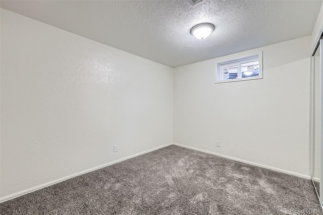 basement featuring a textured wall, a textured ceiling, baseboards, and carpet floors