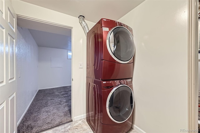 laundry room with carpet flooring, baseboards, and stacked washing maching and dryer