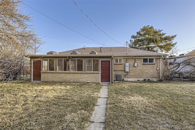 rear view of property with cooling unit, brick siding, a lawn, and a sunroom