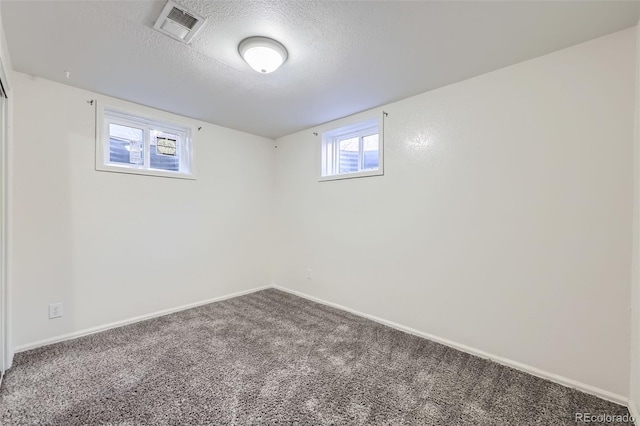 below grade area with baseboards, visible vents, carpet floors, and a textured ceiling