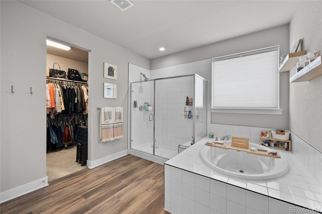 199 Simmental Loop, Castle Rock, CO 80104 - bathroom featuring a garden tub, a shower stall, wood finished floors, a sink, and a walk in closet