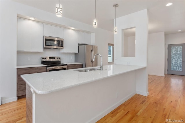 334 Old Stage Rd Unit B, Salida, CO 81201 - kitchen with appliances with stainless steel finishes, a peninsula, white cabinets, backsplash, and light wood finished floors