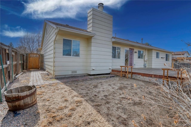 rear view of property featuring fence, a wooden deck, a chimney, crawl space, and a gate