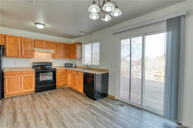 kitchen featuring black appliances, light wood-style flooring, light countertops, and a sink