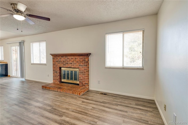 unfurnished living room featuring wood finished floors, a fireplace, visible vents, and baseboards