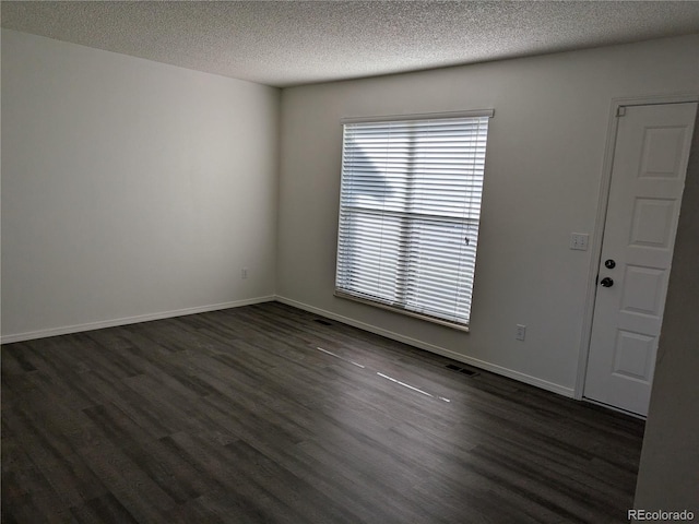 spare room with dark wood finished floors, visible vents, baseboards, and a textured ceiling