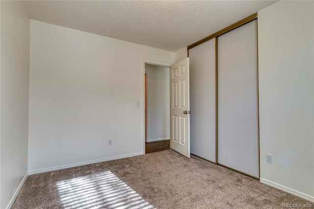 unfurnished bedroom with baseboards, carpet, a closet, and a textured ceiling