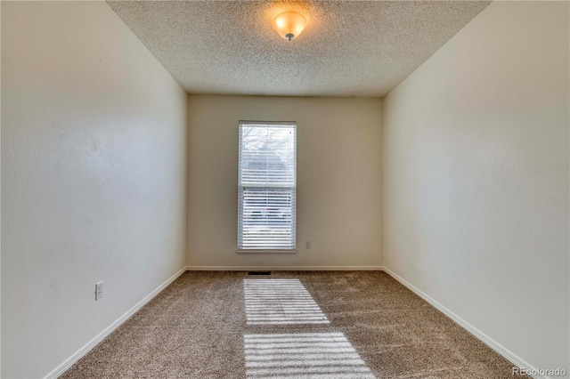 carpeted spare room featuring baseboards and a textured ceiling