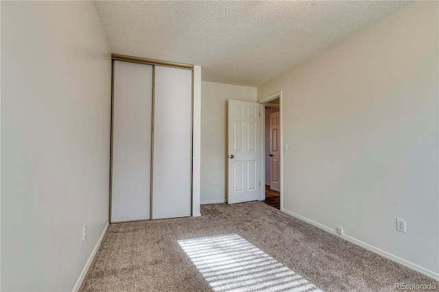 unfurnished bedroom featuring a closet, carpet floors, a textured ceiling, and baseboards