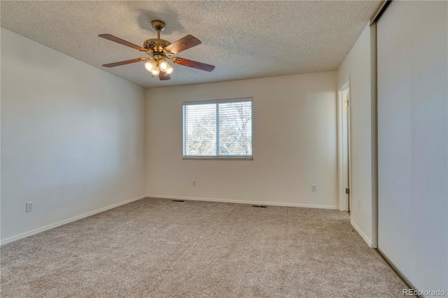 empty room featuring visible vents, a textured ceiling, carpet, baseboards, and ceiling fan