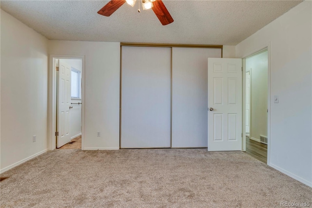 unfurnished bedroom featuring visible vents, carpet floors, a textured ceiling, and a closet