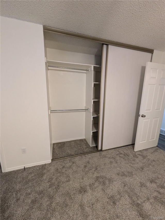 unfurnished bedroom with carpet flooring, baseboards, a closet, and a textured ceiling