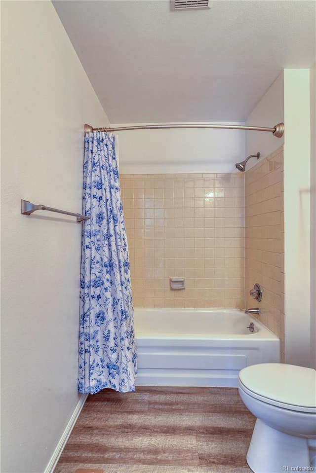 full bath featuring shower / tub combo, toilet, wood finished floors, and visible vents