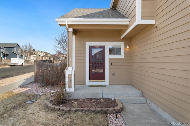 doorway to property featuring a residential view and roof with shingles