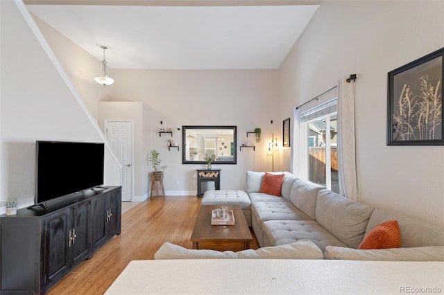 living area with baseboards, lofted ceiling, and light wood-style floors