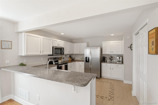 kitchen with visible vents, appliances with stainless steel finishes, a peninsula, and white cabinetry