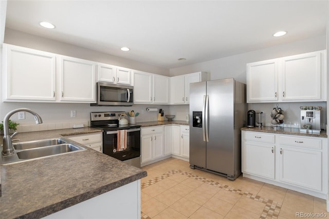 kitchen featuring dark countertops, recessed lighting, appliances with stainless steel finishes, white cabinetry, and a sink