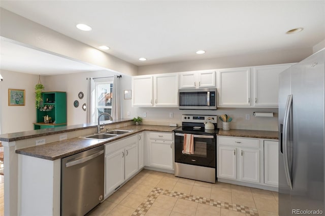 kitchen featuring recessed lighting, appliances with stainless steel finishes, a peninsula, white cabinetry, and a sink