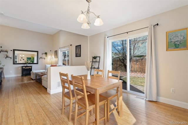 dining room featuring light wood-type flooring, visible vents, baseboards, and an inviting chandelier