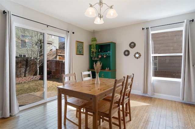 dining room featuring light wood-style flooring, a notable chandelier, and baseboards