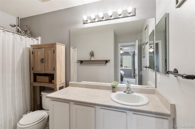 full bath featuring curtained shower, toilet, vanity, and a textured wall