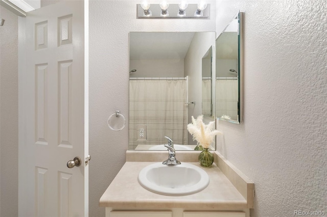 full bathroom featuring a shower with shower curtain, vanity, and a textured wall