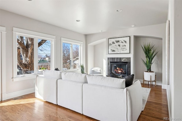 living room featuring wood finished floors, a premium fireplace, baseboards, and recessed lighting
