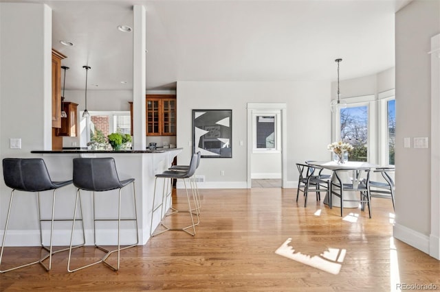 kitchen featuring a kitchen breakfast bar, baseboards, dark countertops, and light wood-style flooring
