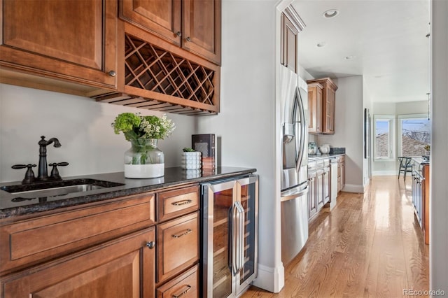 indoor bar featuring beverage cooler, light wood-style flooring, stainless steel refrigerator with ice dispenser, baseboards, and recessed lighting