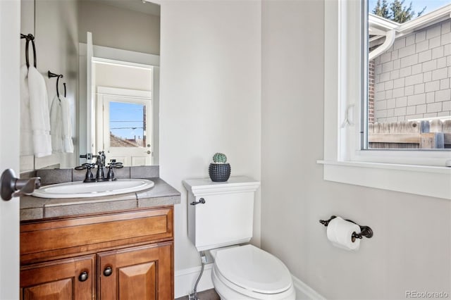 bathroom with toilet, baseboards, and vanity