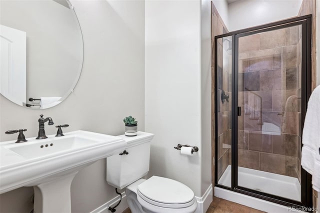 bathroom featuring a stall shower, baseboards, toilet, and a sink