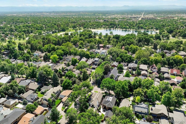 aerial view of residential area featuring a nearby body of water and a heavily wooded area