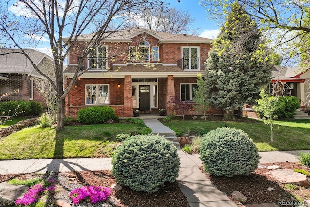 1215 S Ogden St, Denver, CO 80210 - view of front facade featuring brick siding, a balcony, and a front lawn