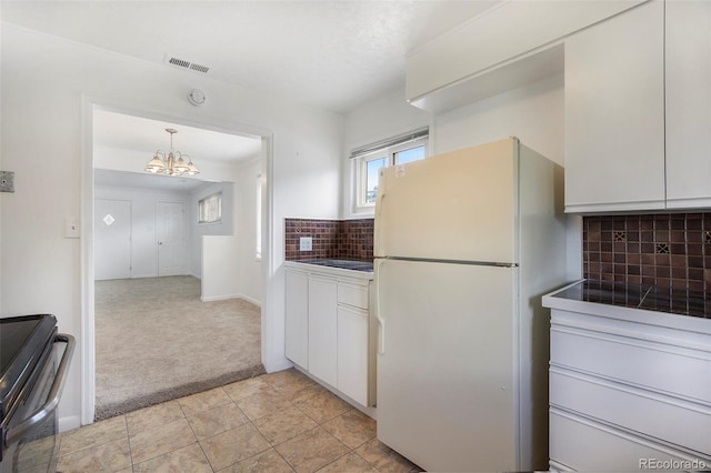 1303 Havana St, Aurora, CO 80010 - kitchen featuring freestanding refrigerator, stove, light colored carpet, a chandelier, and decorative backsplash