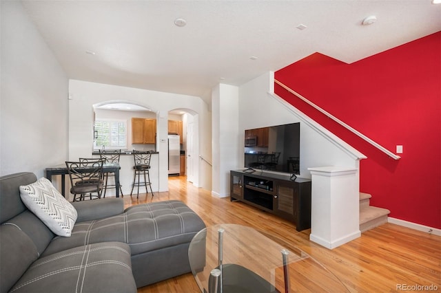 767 Roslyn St Unit 20, Denver, CO 80230 - living room featuring baseboards, arched walkways, light wood-style flooring, and stairway